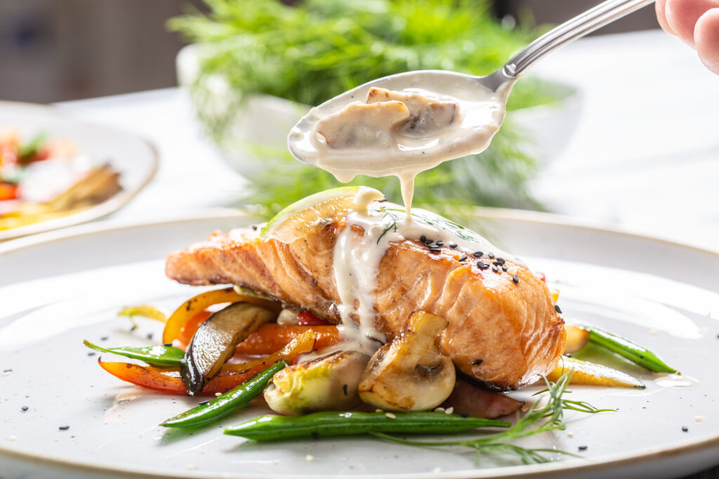The Mansion Restaurant - salmon with vegetables and mushroom sauce poured over it on a plate.