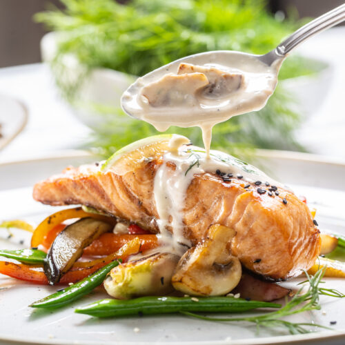 The Mansion Restaurant - salmon with vegetables and mushroom sauce poured over it on a plate.