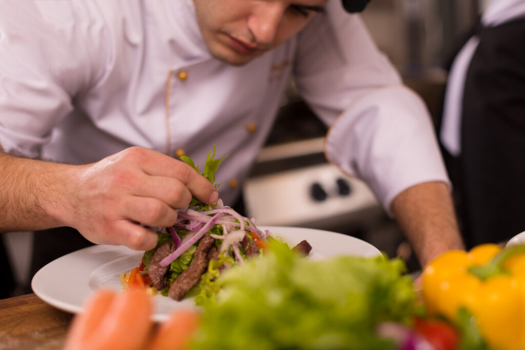 Top Chef Vibes - Cook chef decorating garnishing prepared meal dish on the plate in restaurant commercial kitchen